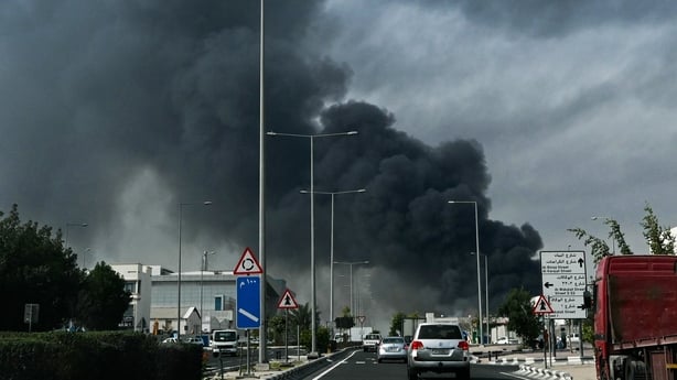 Motorists drive past a plume of smoke rising in Doha