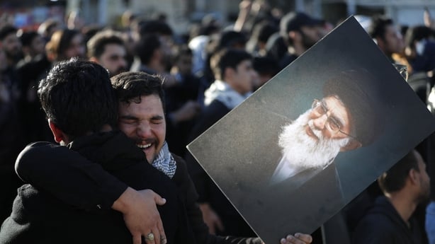 Iraqi Shiites Muslim men grieve as one holds up the image of killed Iranian supreme leader Ayatollah Ali Khamenei, during a symbolic funeral the day after his assassination, in the district of Sadr City, in Baghdad on March 1, 2026. Iran's supreme leader since 1989 and sworn enemy of the West, was k