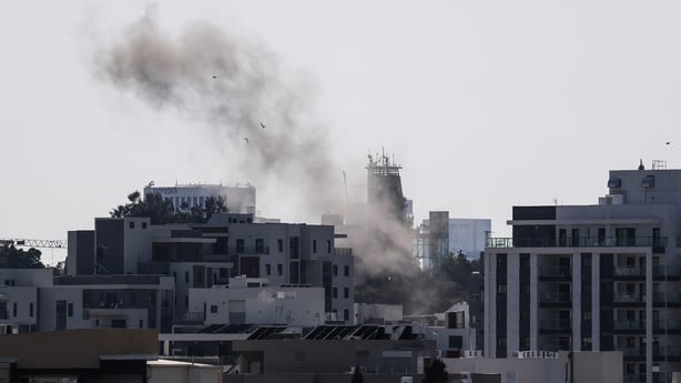 Smoke rises from behind buildings after a projectile struck the area in Tel Aviv