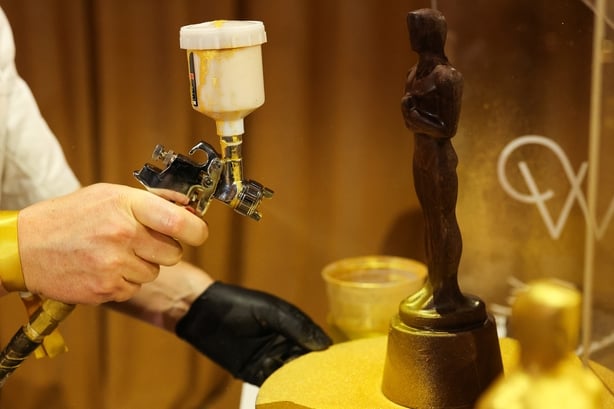 A pastry chef sprays golden food paint on a chocolate Oscar during the 98th Oscars Governors Ball Preview at Ovation Hollywood Complex on 10 March, 2026 in Hollywood, California. (Photo by VALERIE MACON / AFP)