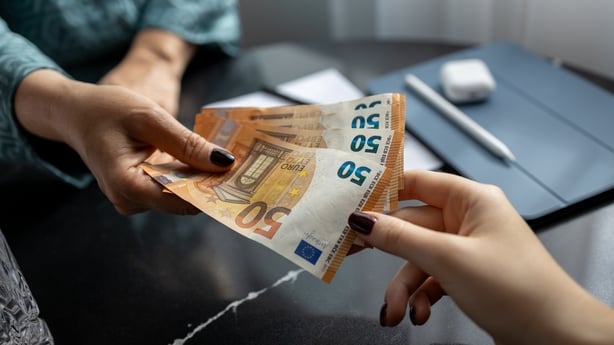 Women handing euro banknotes to each other