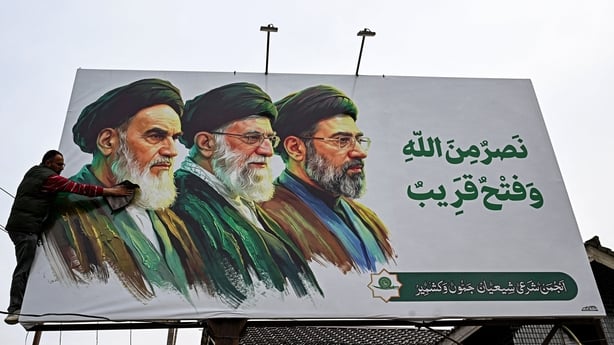 - A man cleans a billboard featuring Iran's late supreme leaders Ayatollah Ruhollah Khomeini (L) and Ayatollah Ali Khamenei (C) next to newly elected supreme leader Ayatollah Mojtaba Khamenei, on the outskirts of Srinagar on March 23, 2026.