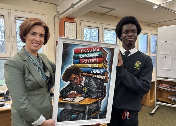 A woman and a teenager hold a piece of artwork between them