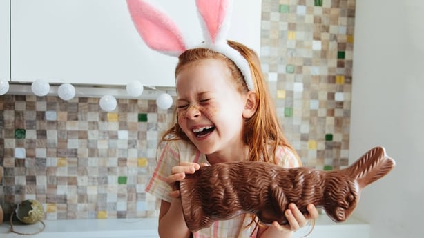 young girl holding chocolate bunny and laughing