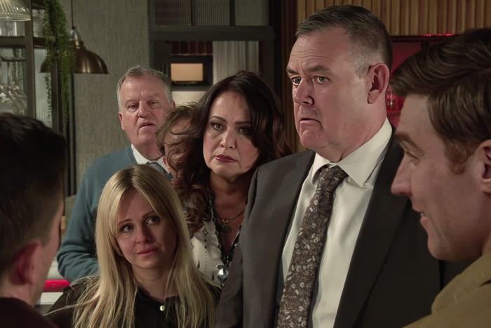 Brian, David, Christina, Sarah Lou and George look towards Todd and Theo in the bistro in a scene from Coronation Street