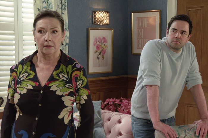 Maggie stands frozen in the Rovers living room with Ben behind her in a scene from Coronation Street