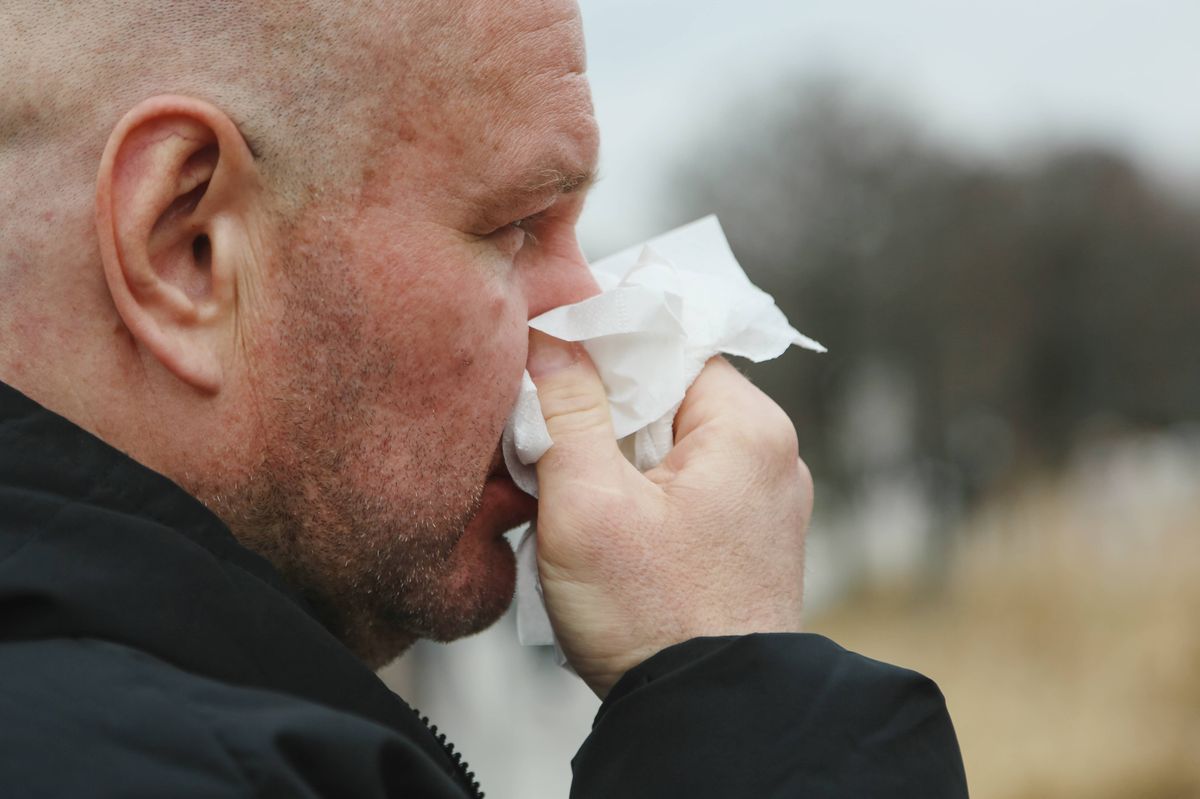 Mature Adult Man Suffering Spring Allergy, Sneezing And Blowing Nose At The City Street