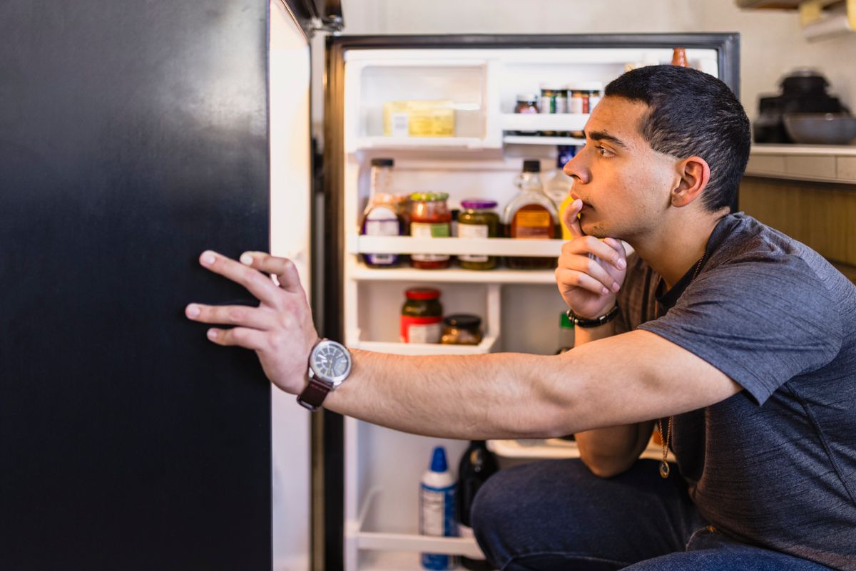 A man looking inside his refrigerator for something to eat