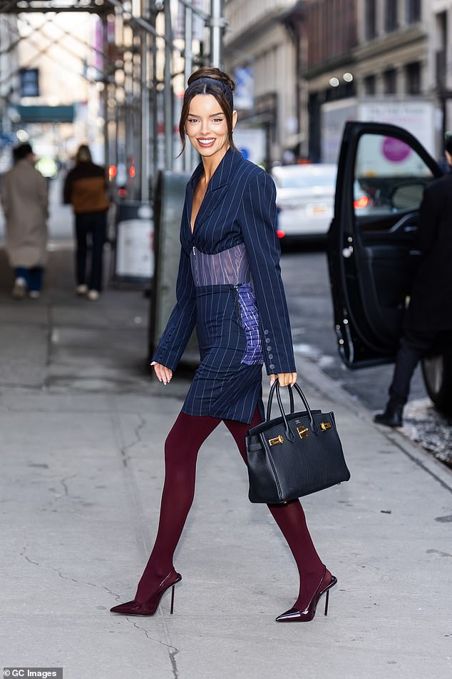 The reality star showed off her figure in the smart navy dress which cinched in at the waist with a corset and elevated her frame in a pair of towering burgundy heels