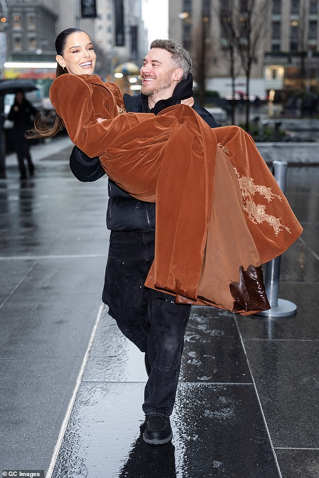 The star beamed from ear to ear as she was swept off her feet by a pal to avoid getting her outfit wet in the rainy weather