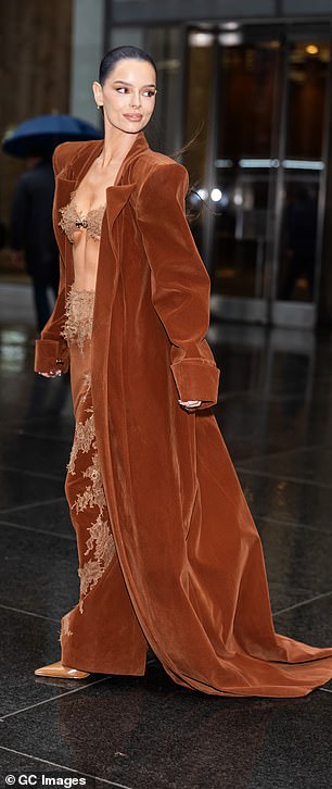 The stylish ensemble featured a structured longline velvet coat with dramatic shoulder pads, teamed with a skimpy lace bra and a matching burnt orange velvet skirt with semi-sheer nude lace trims
