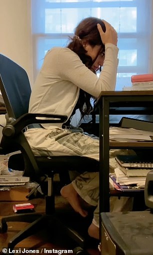 Seated at a writing desk, Lexi struggles to record her memories in the blank pages of a journal after beginning a written sentence with the words 'He was'