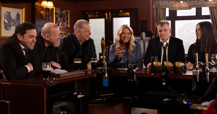 Cassie and Steve stand beside two of Jim's army mates in the Rovers in Coronation Street