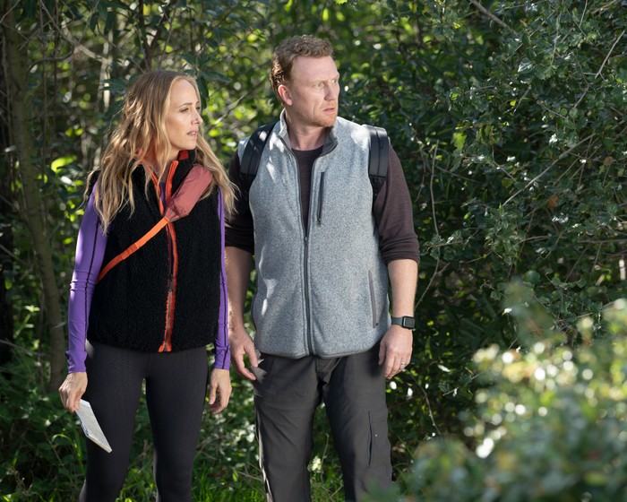 Kim Raver as Dr Teddy Altman and Kevin McKidd as Dr Owen Hunt stand in outdoor wear in a forest setting for Grey's Anatomy.