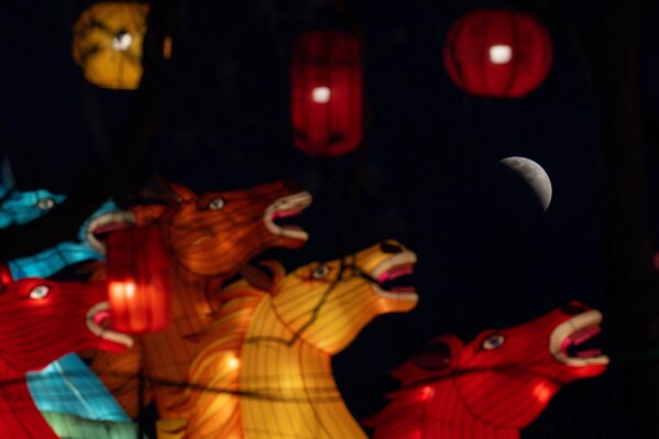 The moon is seen shortly before total eclipse near horse shape lanterns in Beijing, Tuesday, March 3, 2026. (AP Photo/Ng Han Guan)