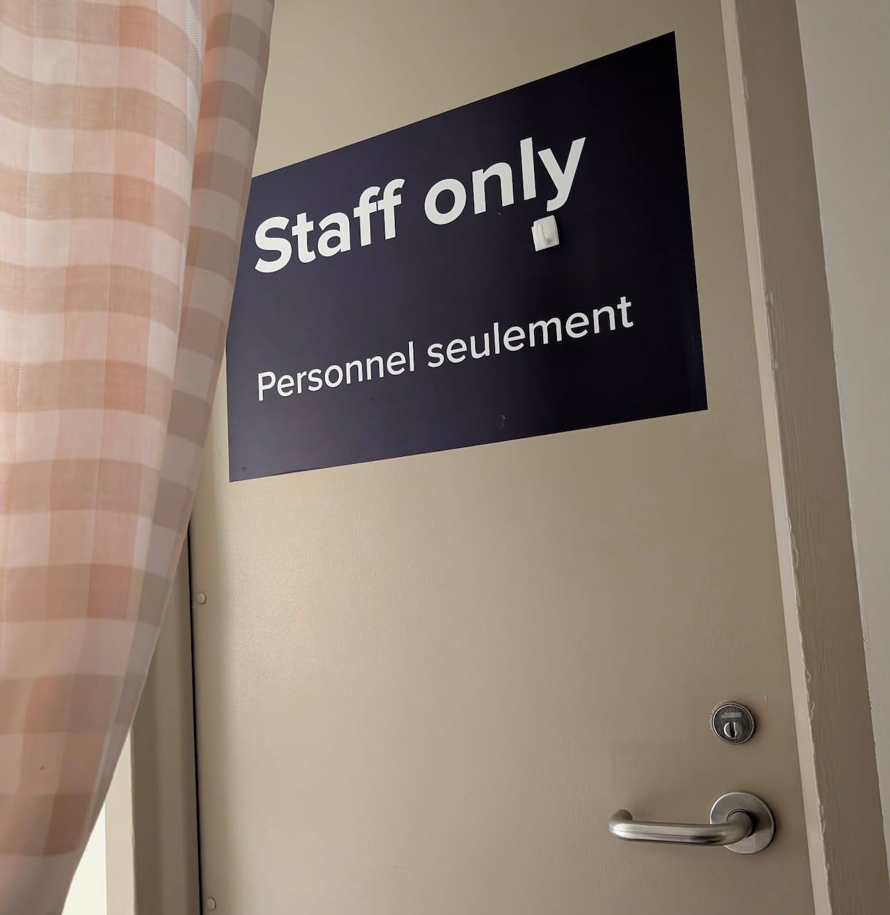 A curtain is pulled back to show a brown door labeled "staff only."