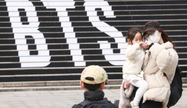 A family of foreign tourists poses in front of a promotional ad for a concert by K-pop boy band BTS, on the steps of the Sejong Center for the Performing Arts in Jongno District, Seoul, March 11. Yonhap