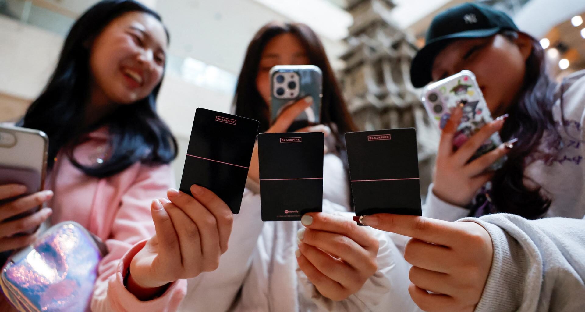 Fans of K-pop band BLACKPINK take a picture of cards related to the band