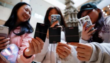 Fans of K-pop band BLACKPINK take a picture of cards related to the band