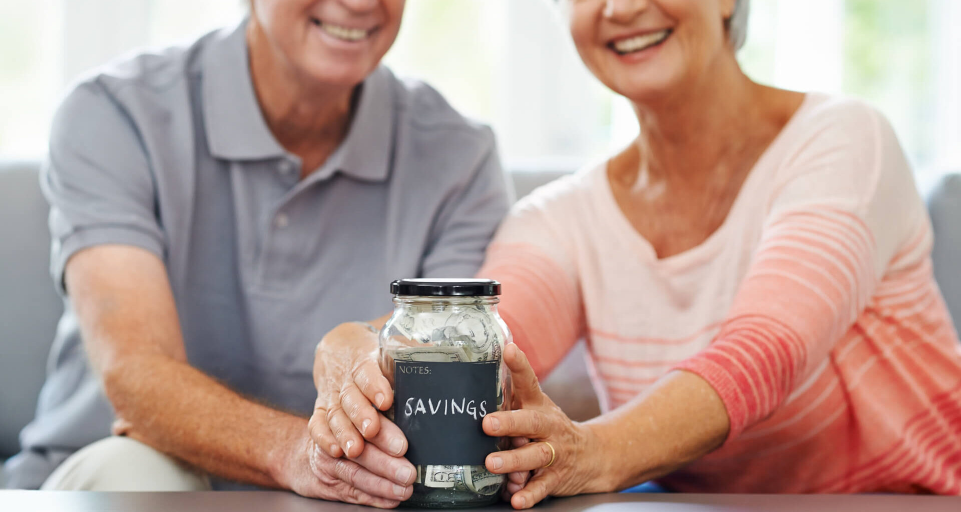 senior couple proudly posing with their savings jar