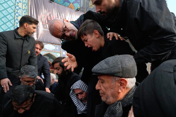 Relatives mourn while the body of Gen. Ali Shamkhani, secretary of Iran's Defense Council and a senior adviser to the Supreme Leader who was killed in a strike, is being buried at the courtyard of the Imamzadeh Saleh shrine in Tehran, Iran, Saturday, March 14, 2026. (AP Photo/Vahid Salemi)