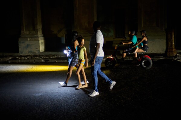 People walk down a street during a blackout in Havana, Monday, March 16, 2026. (AP Photo/Ramon Espinosa)