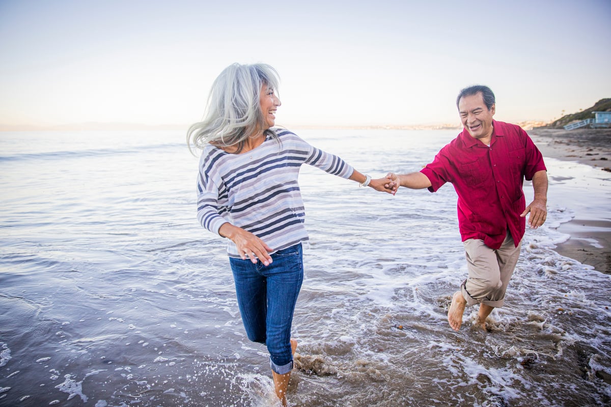 A retired couple walk in the surf.