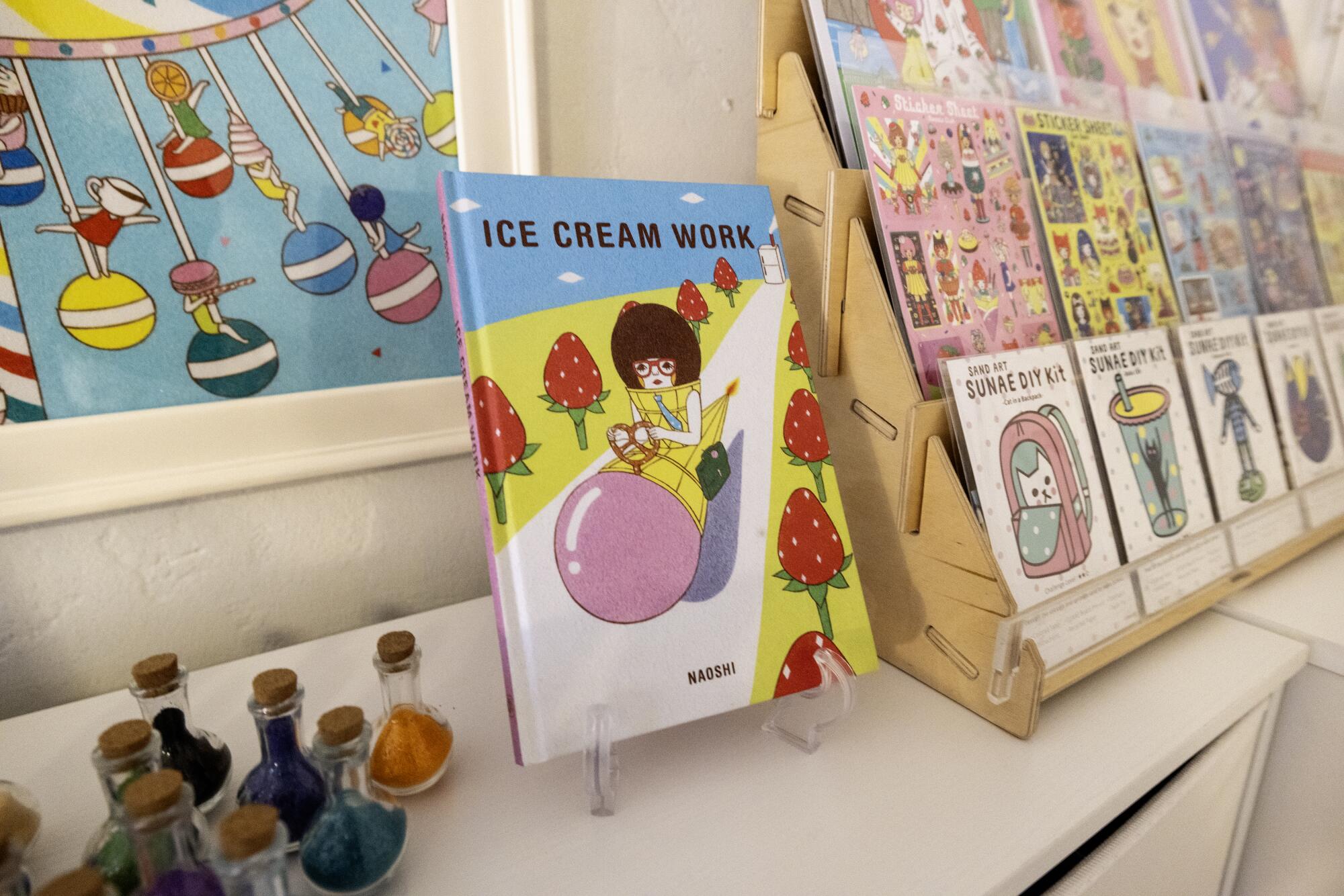 Colorful sand art kits and a picture book showing a woman driving a car with a pretzel for a wheel