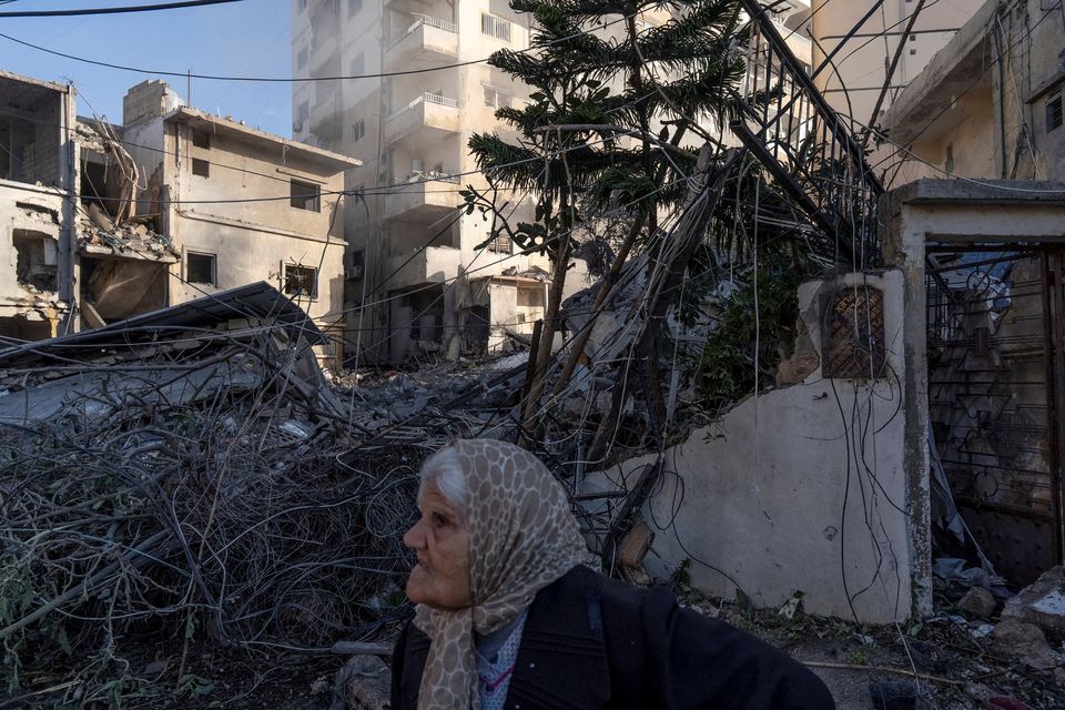 A woman stands next to a building destroyed by an Israeli strike, amid escalating hostilities between Israel and Hezbollah, as the U.S.-Israeli conflict with Iran continues, in Tyre, Lebanon, March 24, 2026. REUTERS/Manu Brabo     TPX IMAGES OF THE DAY     