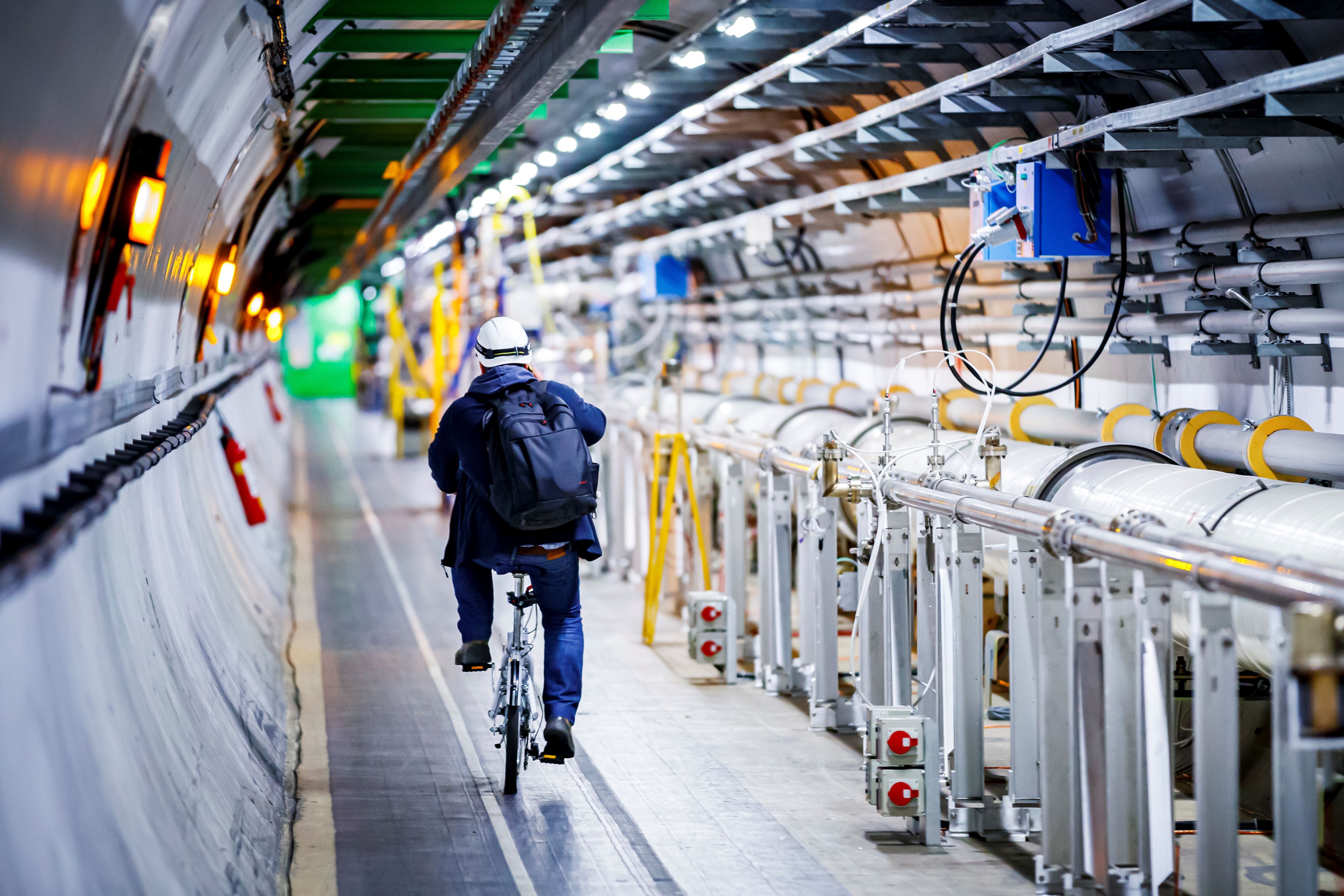 A man rides his bicycle along the underground Large Hadron Collider during its hiatus in 2020