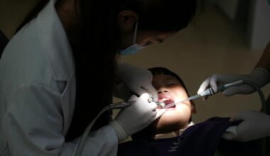 A young child undergoing a dental procedure in a clinic, with a dentist attending.