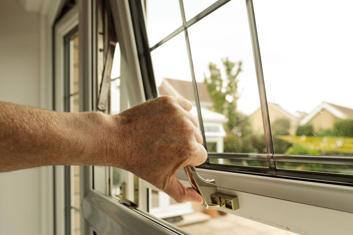 Homeowner seen about to lock a double glazed window seen on the ground level of a property.