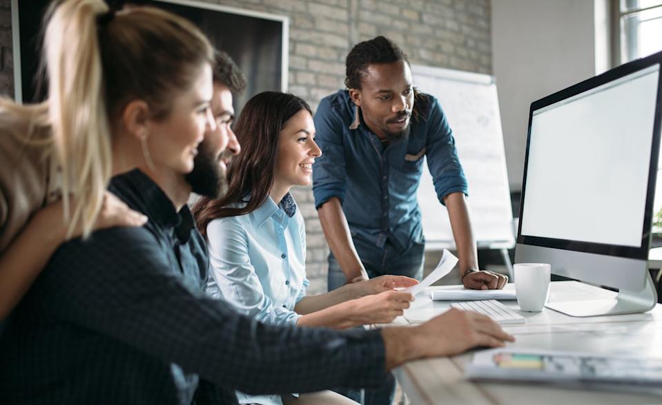 Investors gather around a computer in an office.