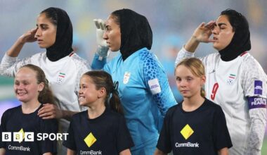 Iranian players salute during the national anthem
