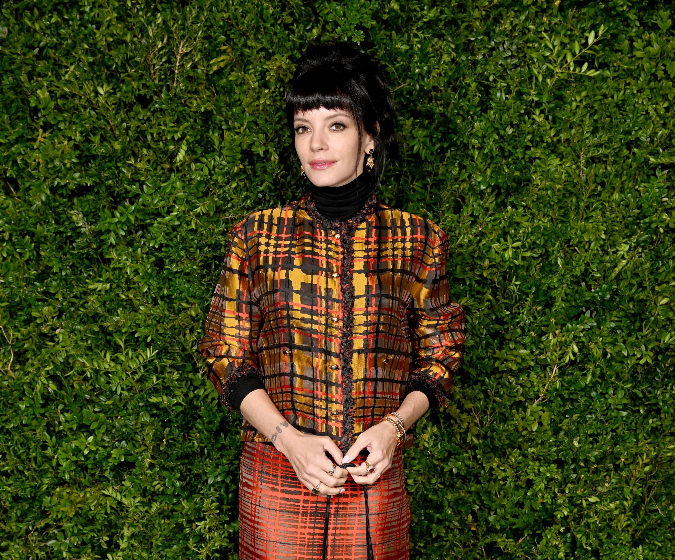 Lily Allen in a plaid jacket and skirt, holding a Chanel purse, at the Charles Finch & Chanel 2026 pre-BAFTA Party.