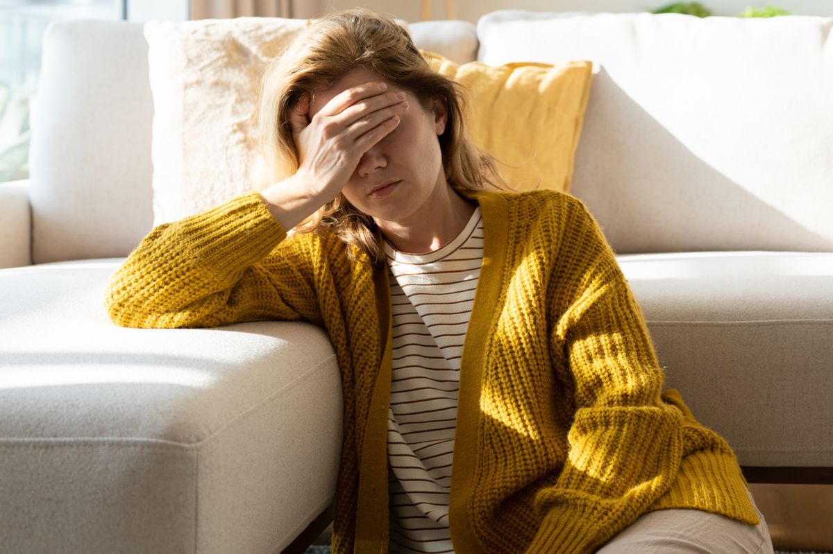 Woman suffering a headache holding her head at home