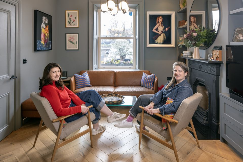 Robyn and Esther in the older part of the house with its original fireplace. Paint colours are sombre, however, the pair lighten the mood with their artworks. Esther describes it as a masculine/feminine vibe. Photo: Tony Gavin