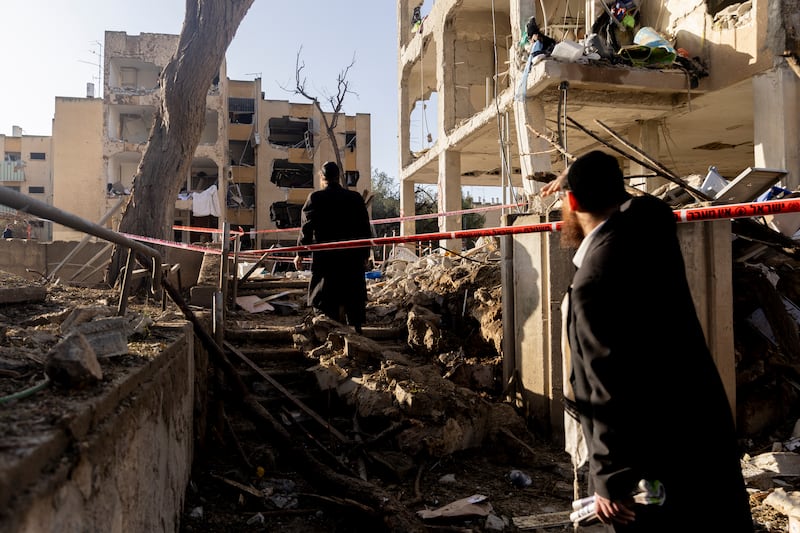 Ultra-Orthodox Jewish men look at destroyed buildings after an Iranian missile strike on March 22nd, 2026 in Arad, Israel. Photograph: Getty Images