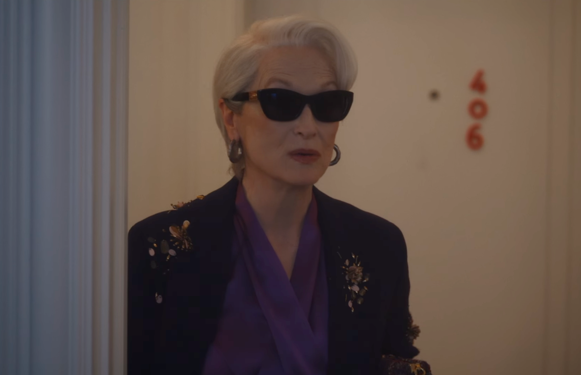 a stylish figure standing near a door with the number 406