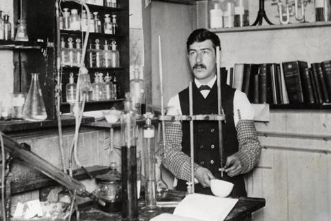 An old black and white photo of Moses Gomberg working in his lab