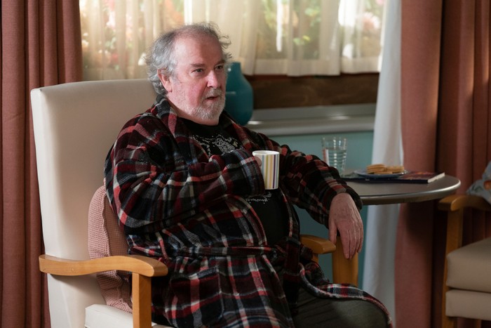 Nigel sits in a dressing gown in his carehome in a scene from EastEnders
