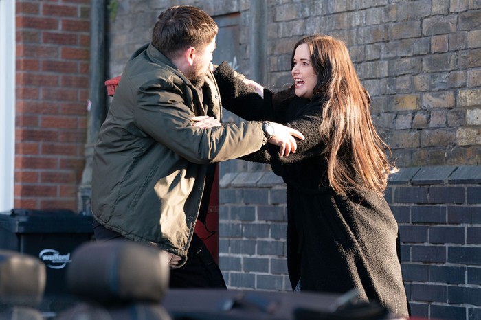 Lauren pushes away a thuggish man in a scene from EastEnders