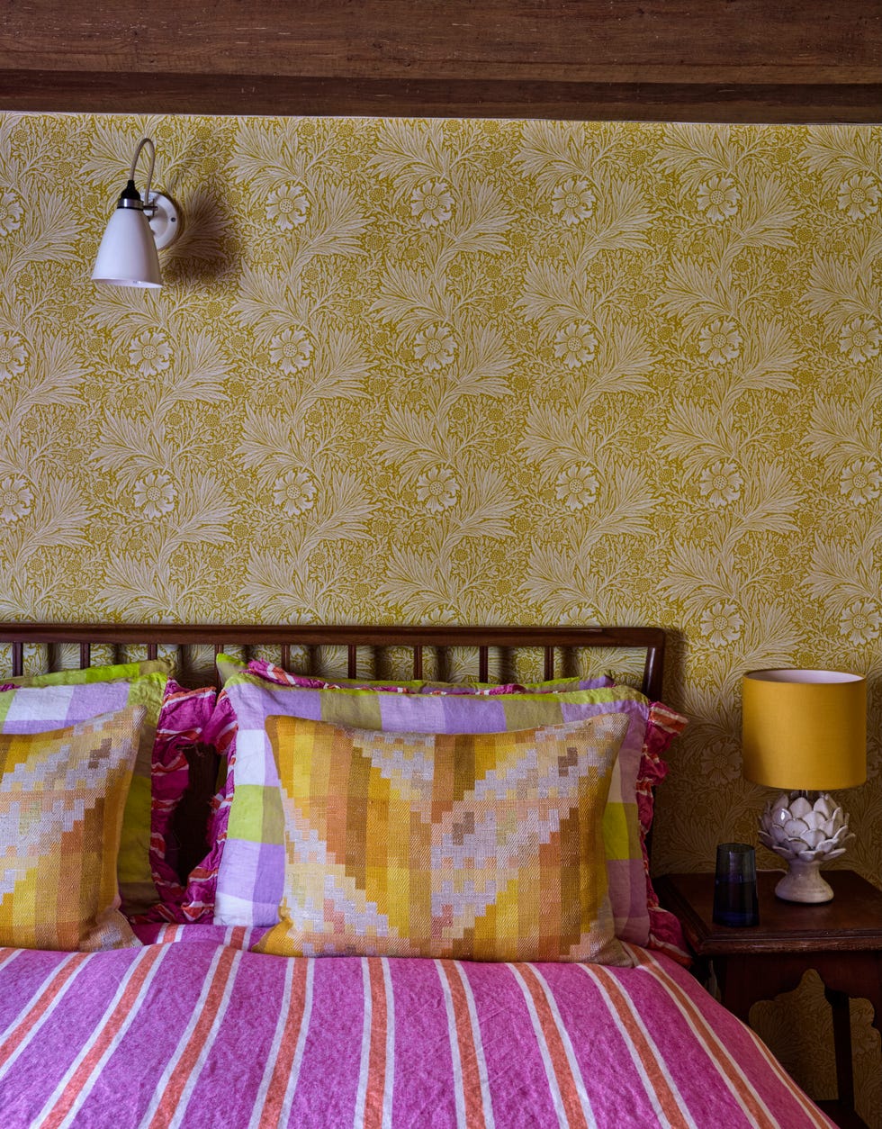 cosy bedroom with patterned wallpaper and colourful bedding