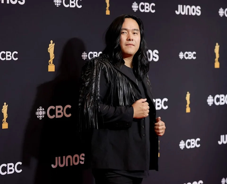 Person in fringed jacket poses on Junos red carpet backdrop marked with CBC and Junos logos