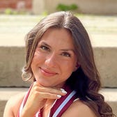 Amanda kneels down and poses with her graduation cap and stole.