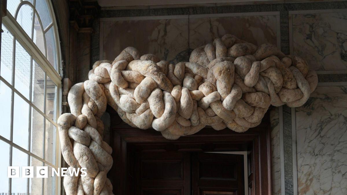 Large knotted woollen shapes above a door frame in a house. The walls are marbled.