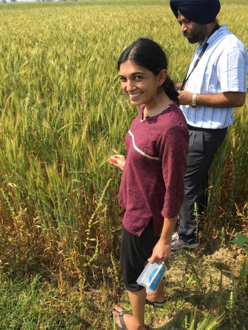 A women in india in front of a field conducting research.