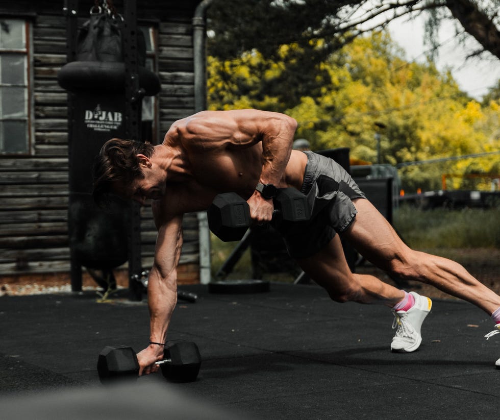 man performing an exercise with dumbbells outdoors