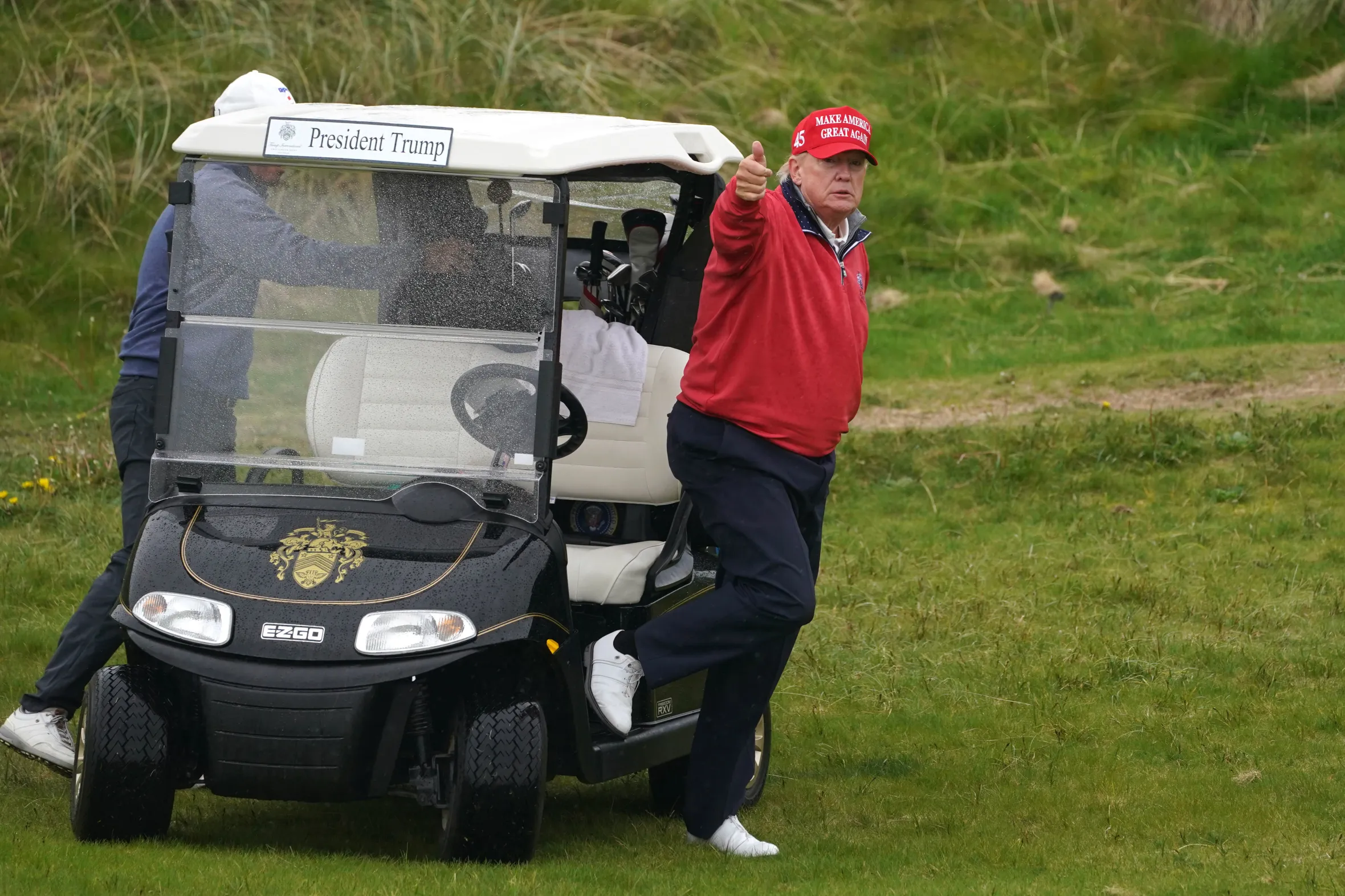 Donald Trump, wearing a red "Make America Great Again" hat, gives a thumbs up while playing golf in Doonbeg, Co. Clare.