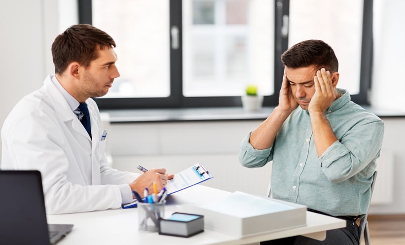 Adult patient with cluster headache symptoms speaking with a clinician about topiramate prophylaxis
